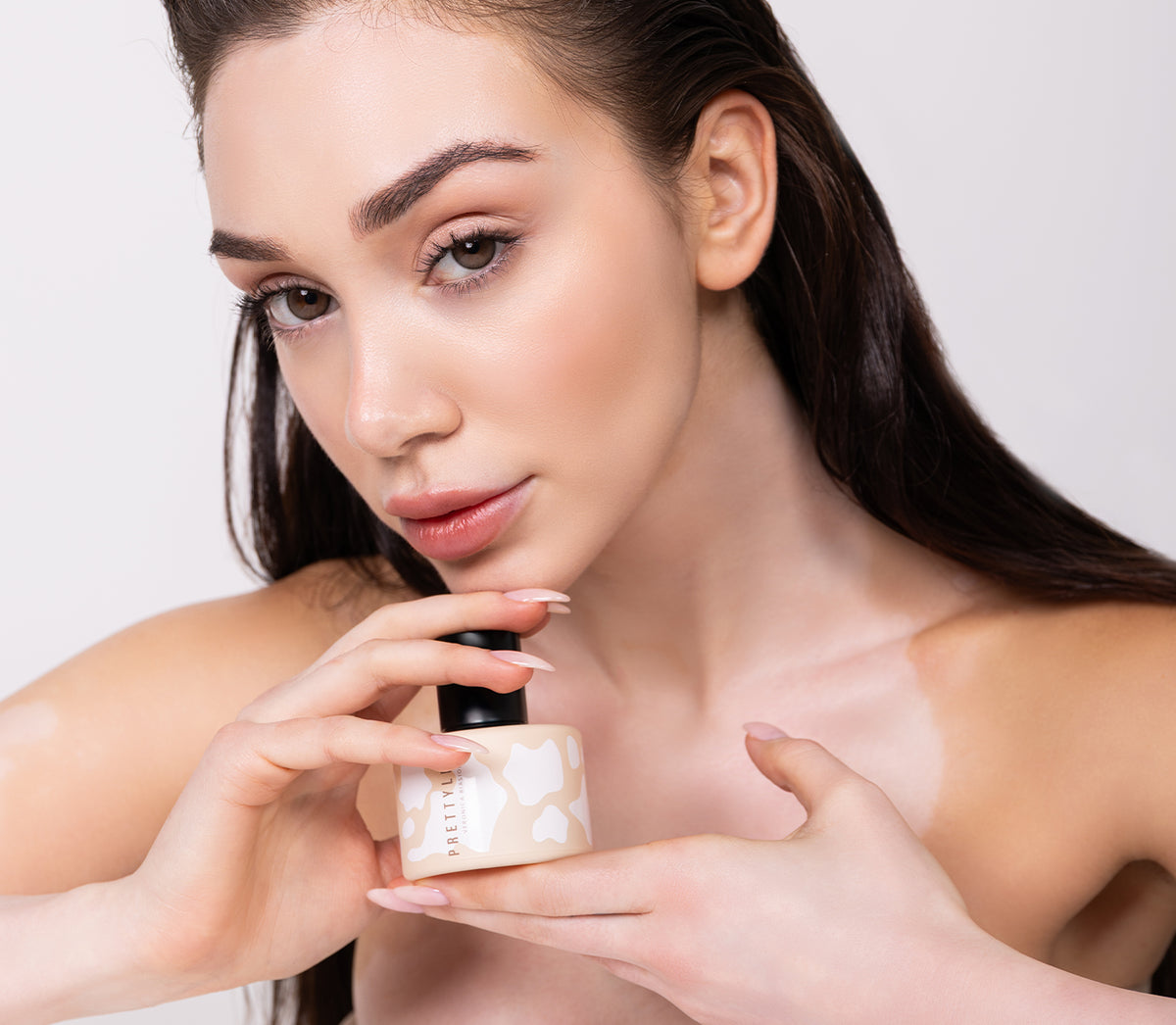 Žena držící béžový flakon parfému Prettyligo pod bradou – MrRizz